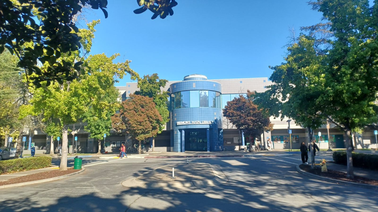 Fremont Main Library on a sunny day, a local civic building with trees and a paved drive in the foreground.