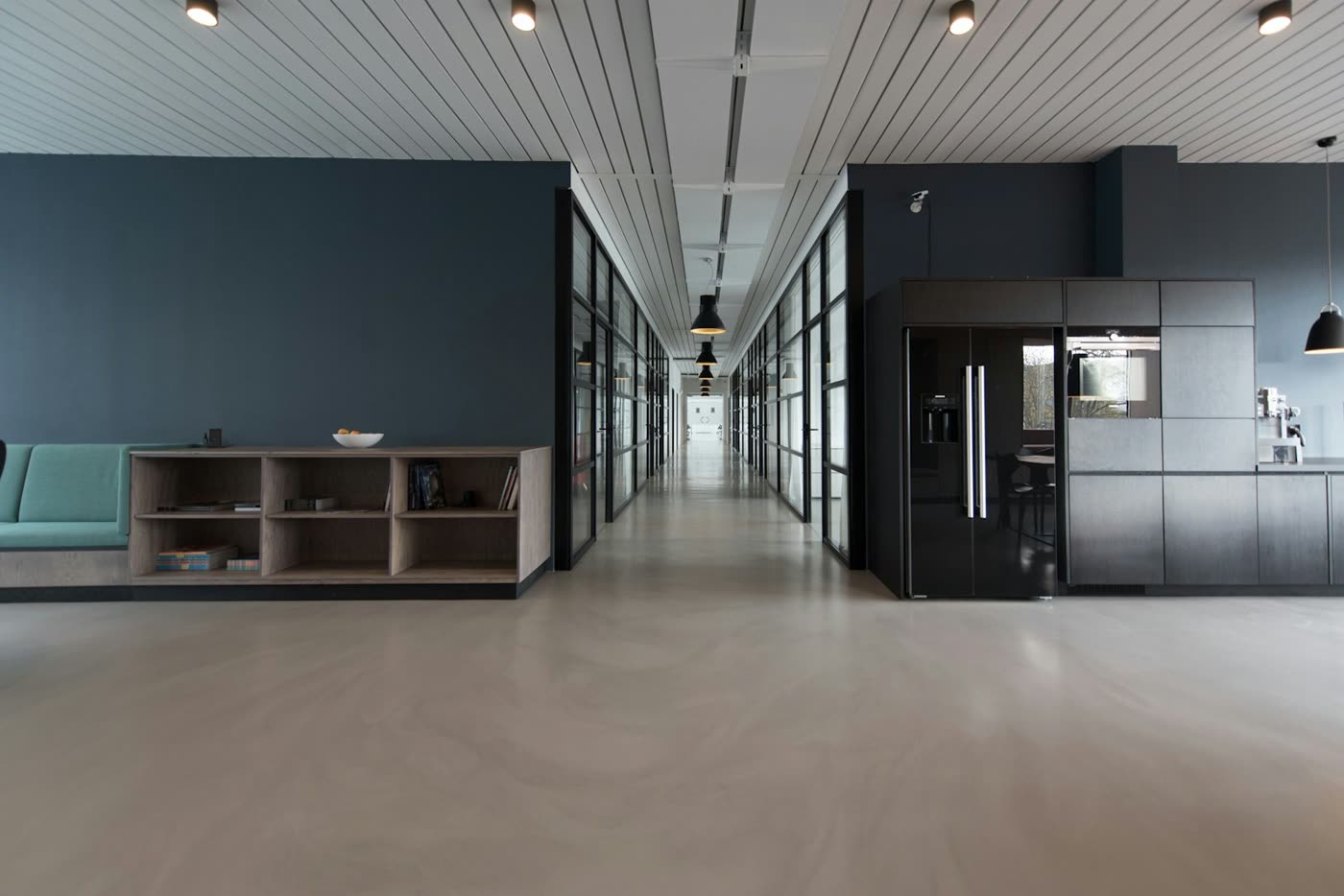 Quiet modern office interior with a long corridor, wood shelves, and glass-walled rooms. No portraits.